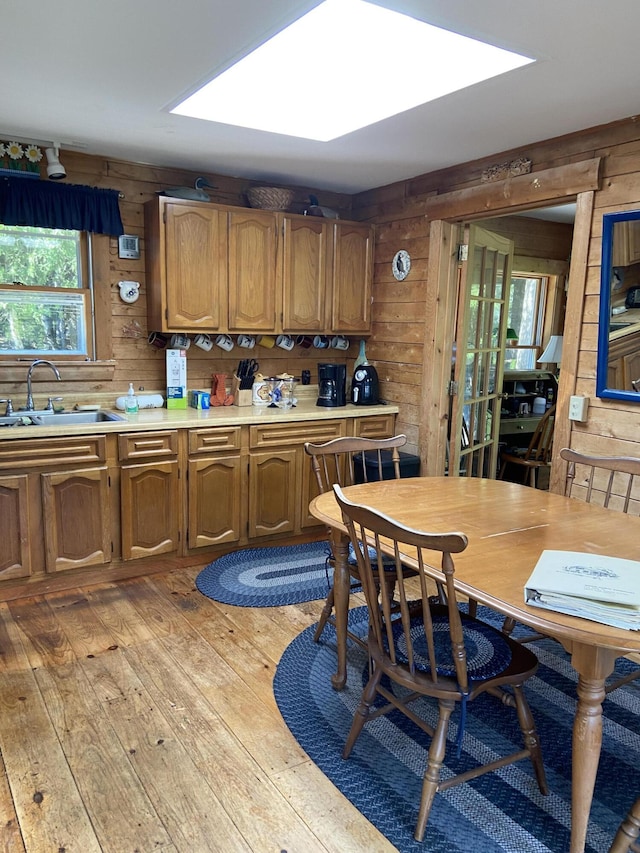 91 Mcsorley Rd, Great Cranberry, Cranberry Isles, ME 04625 - kitchen featuring wooden walls, brown cabinetry, light countertops, light wood-type flooring, and a sink