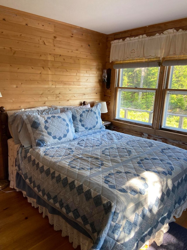 bedroom with wood walls and hardwood / wood-style floors