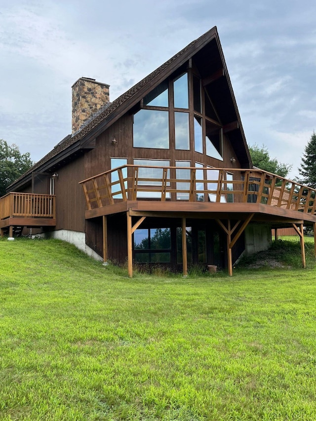 rear view of property featuring a wooden deck and a lawn