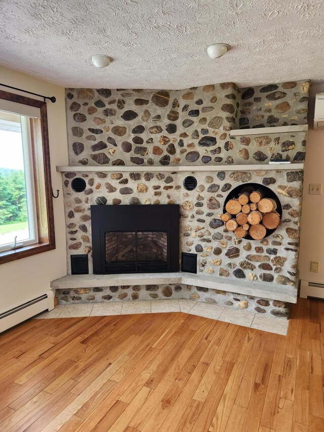 interior details featuring a textured ceiling, a fireplace, hardwood / wood-style floors, and a baseboard radiator