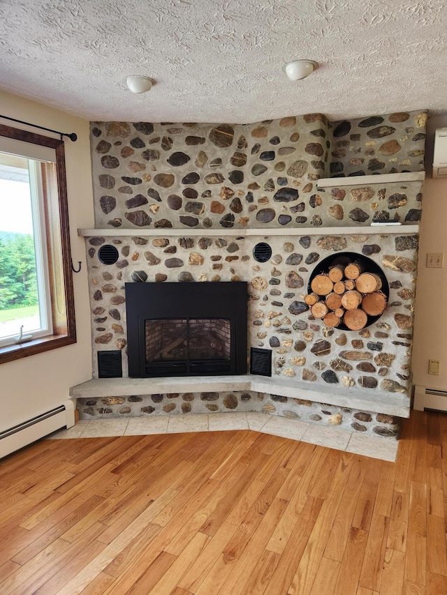 room details featuring a textured ceiling, a brick fireplace, wood finished floors, and a baseboard radiator