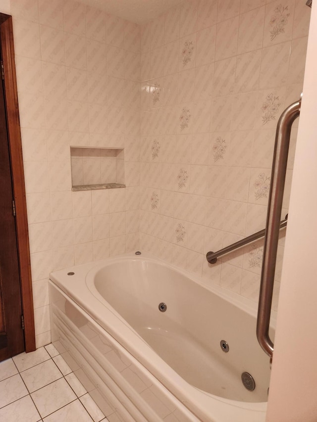 bathroom featuring tile patterned flooring, a tub with jets, and tile walls