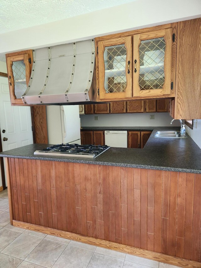 kitchen featuring kitchen peninsula, sink, light tile patterned flooring, and white appliances