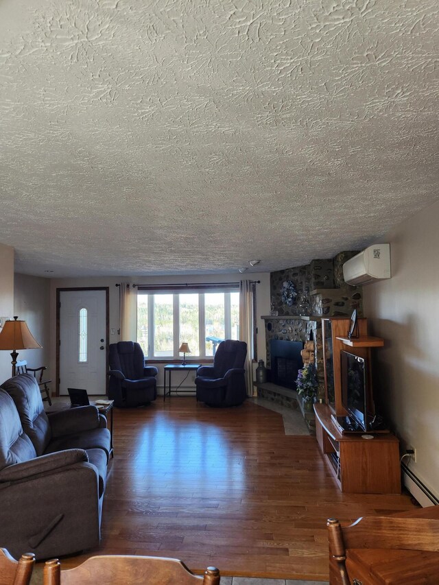 living room featuring baseboard heating, dark hardwood / wood-style flooring, a textured ceiling, and a stone fireplace