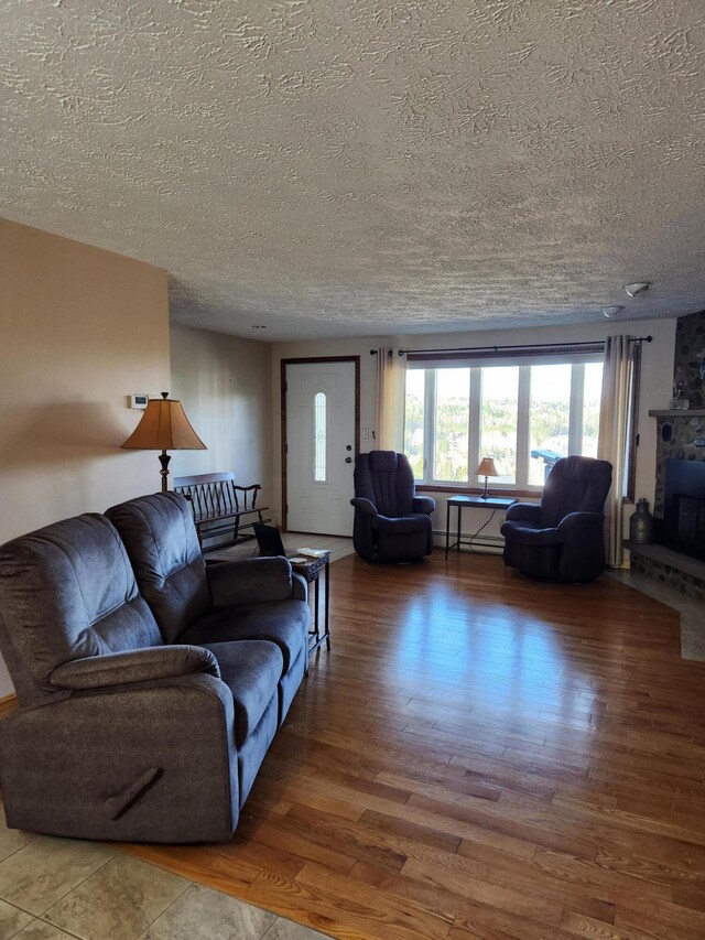 living room featuring hardwood / wood-style floors, a fireplace, a textured ceiling, and a baseboard radiator