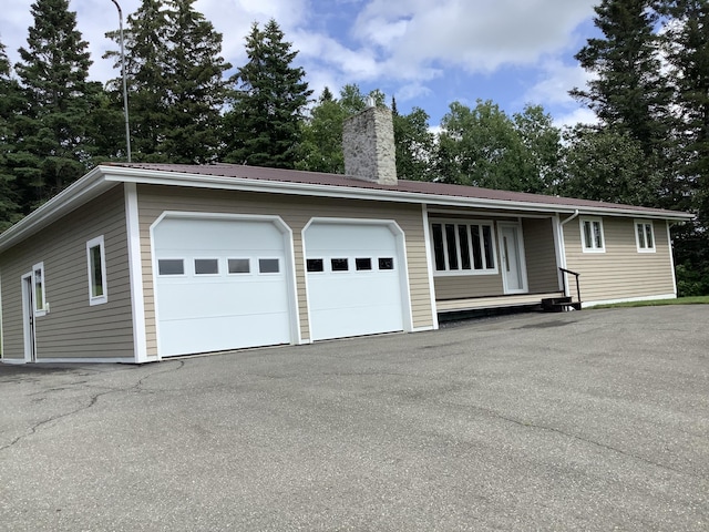 single story home featuring a chimney, a garage, and metal roof