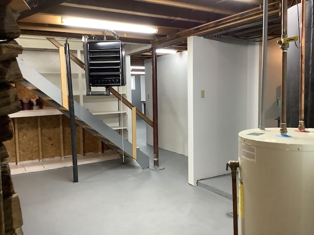 unfinished basement featuring stairs and water heater