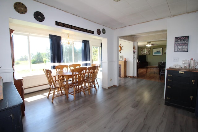 dining space with dark hardwood / wood-style flooring and ceiling fan with notable chandelier