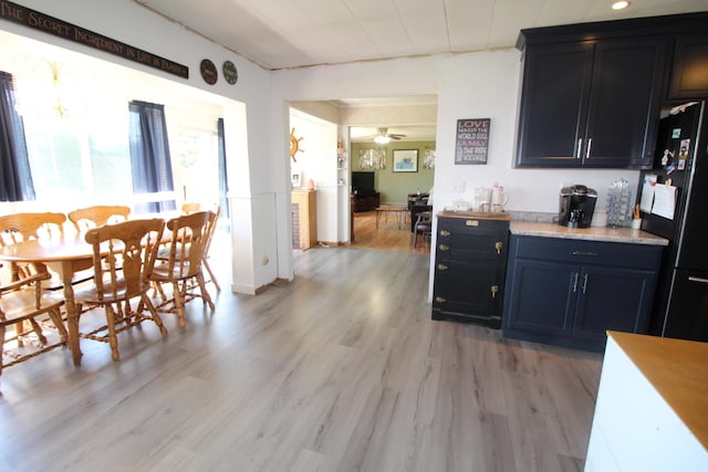 kitchen featuring ceiling fan, light hardwood / wood-style flooring, and black refrigerator