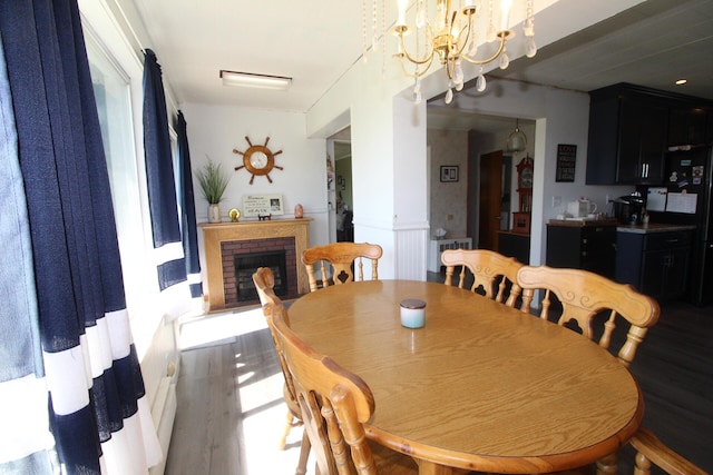 dining space with an inviting chandelier, a fireplace, and hardwood / wood-style floors