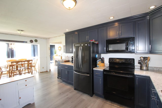 kitchen featuring light stone countertops, black appliances, and light hardwood / wood-style flooring