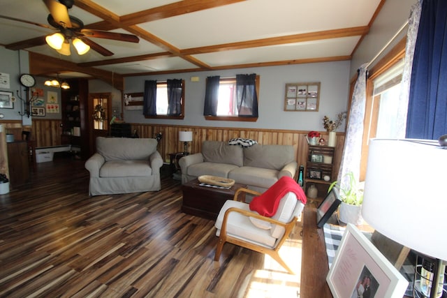 living room with beamed ceiling, dark wood-type flooring, ceiling fan with notable chandelier, and wood walls