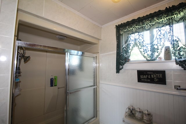 bathroom with a shower with door and crown molding