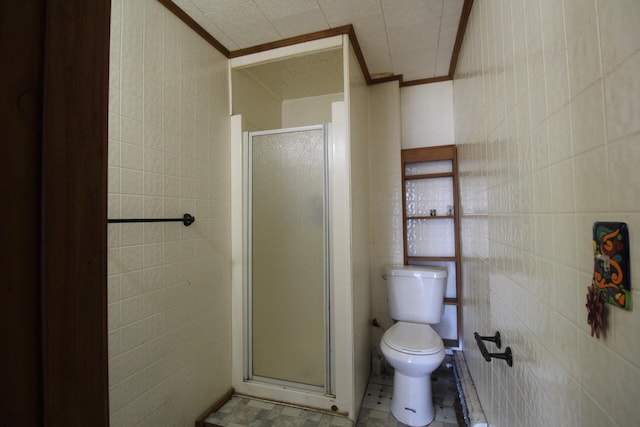 bathroom featuring tile walls, ornamental molding, toilet, and walk in shower