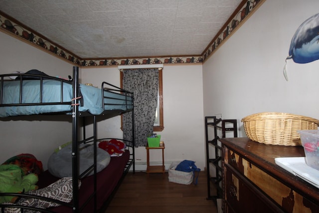 bedroom featuring baseboard heating and dark hardwood / wood-style floors