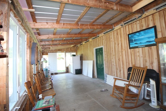 misc room featuring concrete floors, vaulted ceiling, and wooden walls