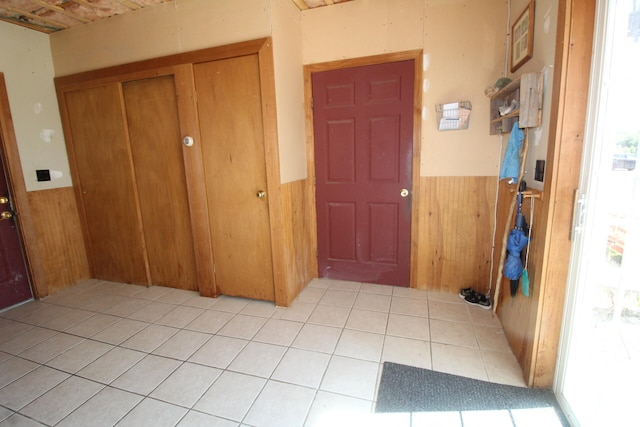 foyer entrance featuring wood walls and light tile patterned flooring