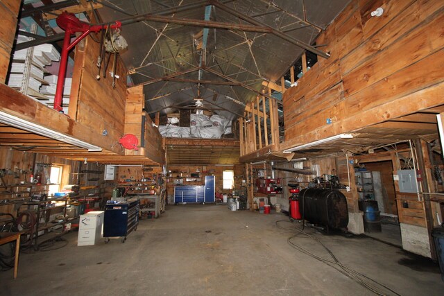 garage featuring electric panel, a workshop area, and wood walls