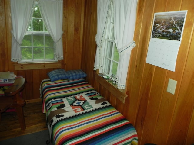 bedroom with wooden walls and dark wood-type flooring