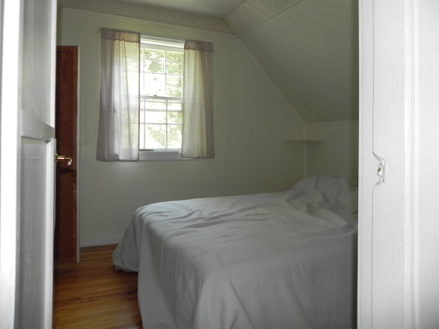 bedroom with vaulted ceiling and hardwood / wood-style floors