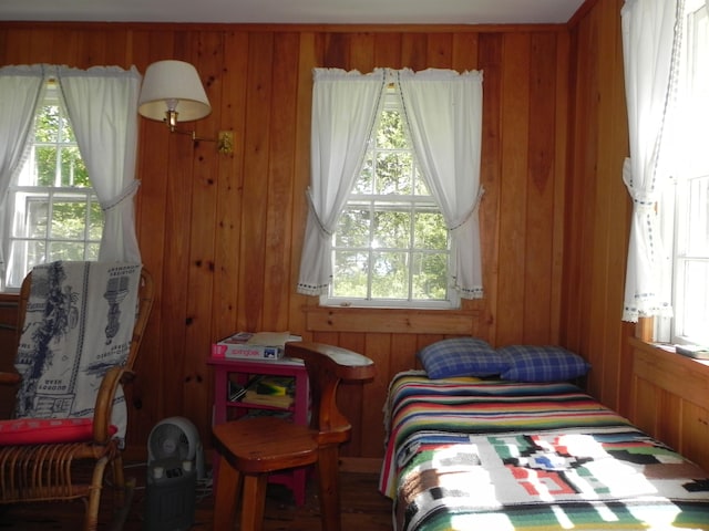 bedroom featuring multiple windows and wooden walls