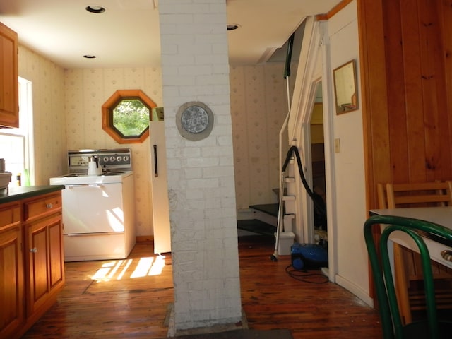 kitchen featuring brick wall, white range, hardwood / wood-style floors, and ornate columns