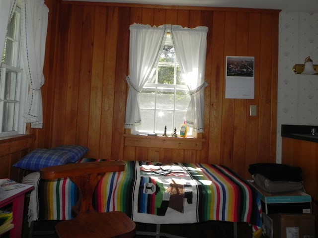 bedroom featuring multiple windows and wooden walls