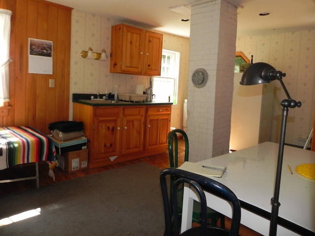 kitchen with sink, brick wall, decorative columns, and dark hardwood / wood-style floors