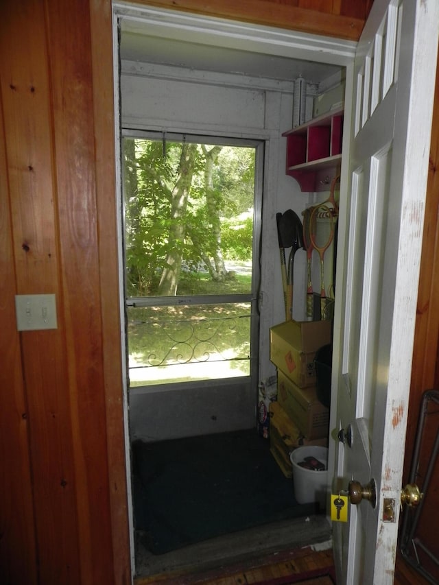 doorway to outside with wood walls