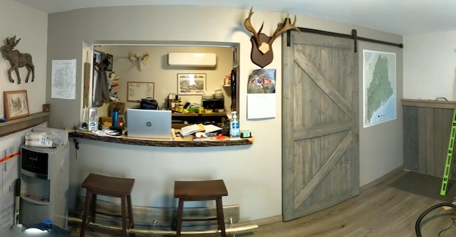 interior space with a barn door, a wall mounted AC, and wood-type flooring