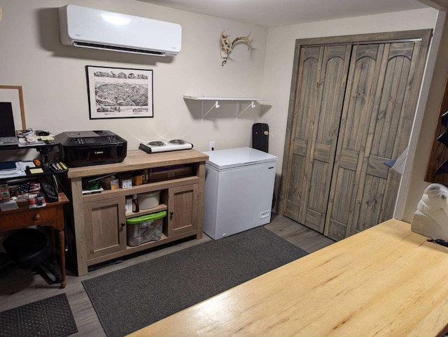 laundry room featuring a wall unit AC and light wood-type flooring