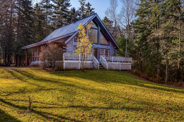 view of front facade featuring metal roof, a deck, log exterior, and a front yard