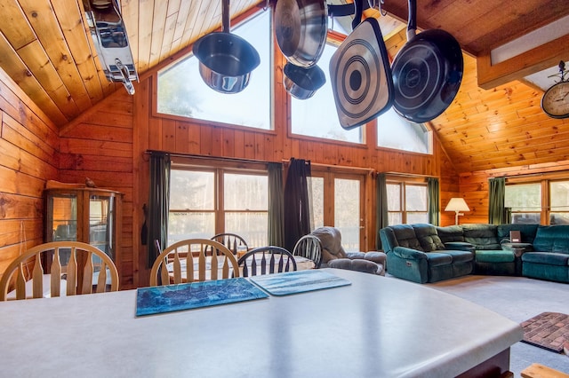 carpeted dining area with wood walls, beam ceiling, and high vaulted ceiling