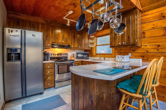 kitchen with wood walls, wooden ceiling, track lighting, and appliances with stainless steel finishes