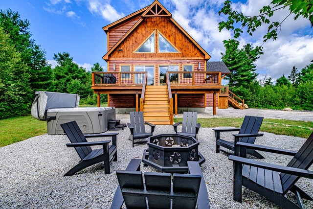 view of patio featuring a hot tub, an outdoor fire pit, and a deck