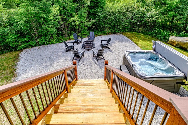 exterior space with a wooden deck, a hot tub, and an outdoor fire pit