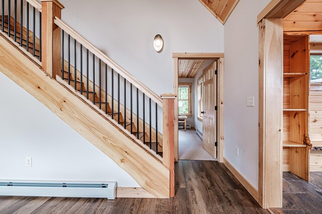 stairs featuring hardwood / wood-style flooring, wooden ceiling, baseboard heating, and vaulted ceiling