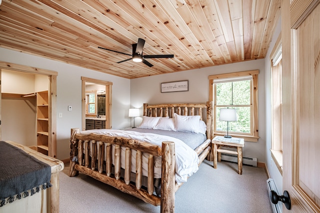 carpeted bedroom with ensuite bath, ceiling fan, a baseboard radiator, a spacious closet, and wooden ceiling