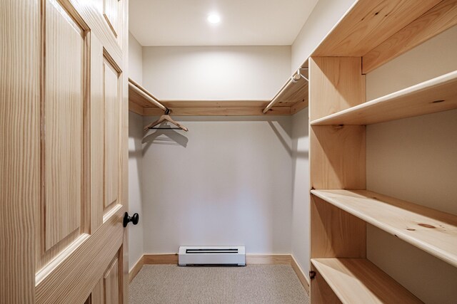 walk in closet featuring baseboard heating and light carpet