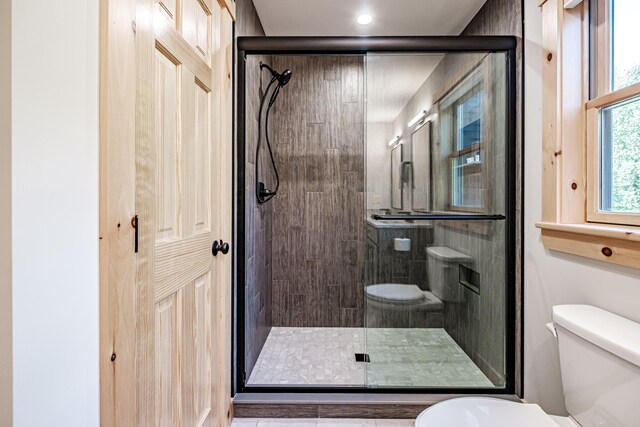 bathroom featuring a shower with shower door and toilet