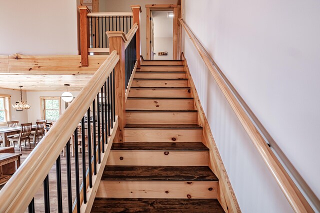 stairway featuring hardwood / wood-style flooring and a notable chandelier