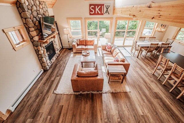 living room with hardwood / wood-style floors, baseboard heating, a fireplace, and an inviting chandelier