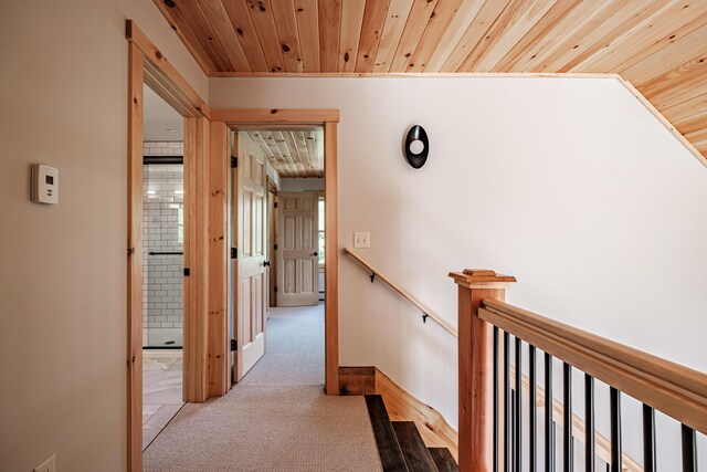 hallway featuring light colored carpet and wood ceiling