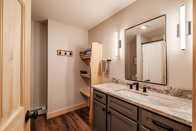 bathroom featuring hardwood / wood-style floors, vanity, and baseboard heating