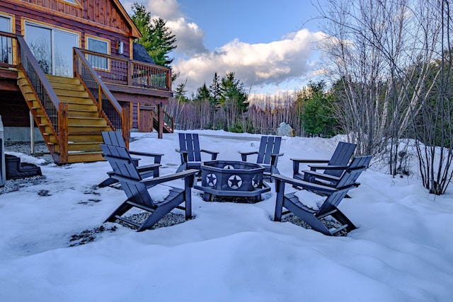 yard layered in snow with a deck and an outdoor fire pit