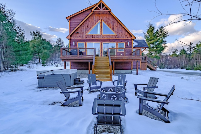 snow covered house featuring a hot tub, a deck, and a fire pit