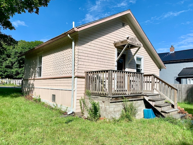 back of property with a lawn and a wooden deck