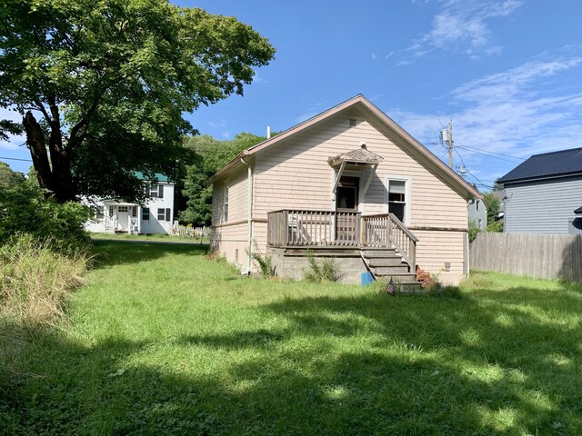 rear view of house featuring a lawn and a wooden deck