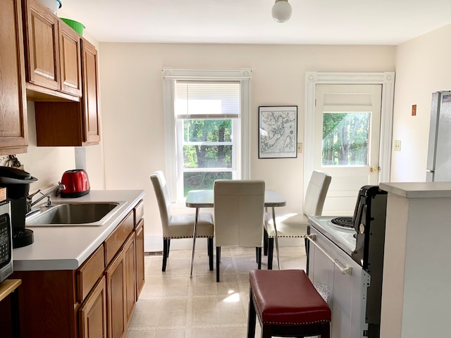 kitchen with light tile patterned floors, white range with electric cooktop, plenty of natural light, and sink