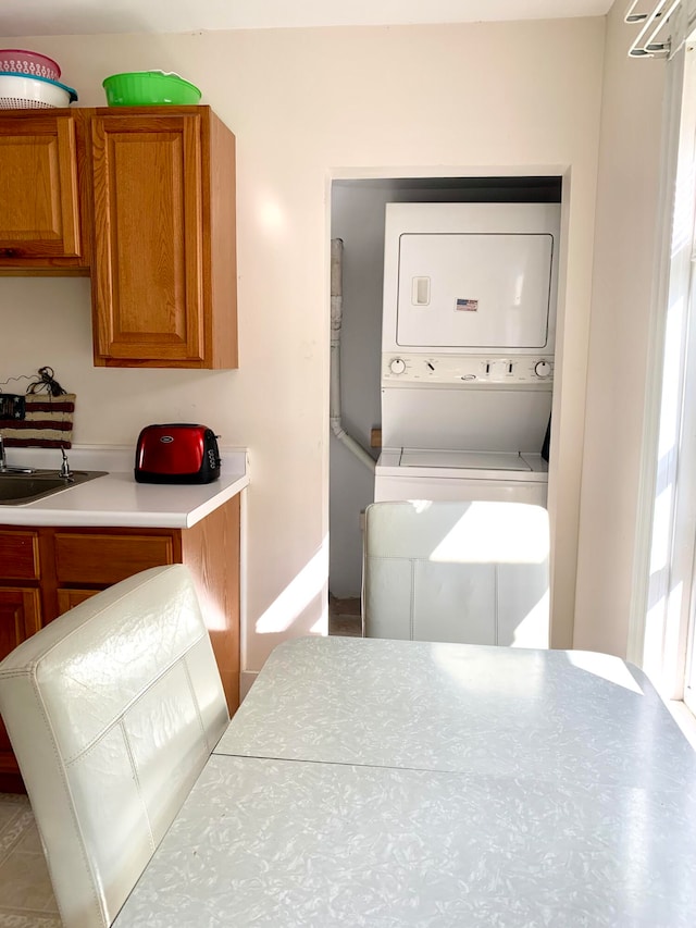 laundry area featuring stacked washer / drying machine and sink